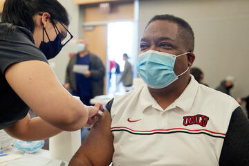 Dr. Whitfield has the injection spot on his arm bandaged by a staff member.