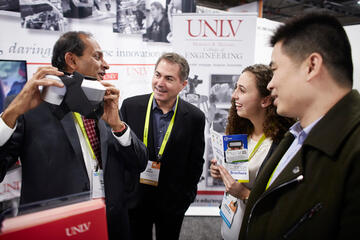 Dean Venkat and President Jessup both testing a virtual reality experience that a neighboring booth had created.