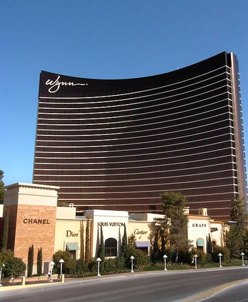 Front side view of the Wynn Las Vegas with stores lined up in front on Las Vegas Blvd.