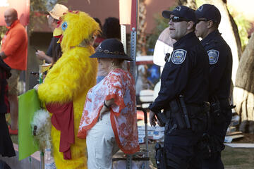 Two police officers standing near someone in a chicken suit.