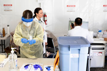 A medical worker in full protective gear examines a sample