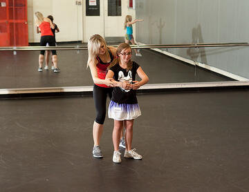 Young girl getting guidance form a dance instructor.