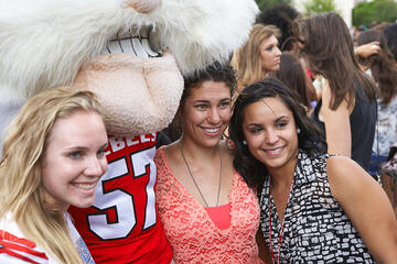 Three young women posing for a picture with Hey Reb the mascot.