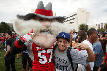 Front side view of Hey Reb the mascot and a student.