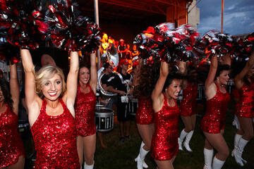 UNLV"s rebel dancers wearing their scarlet red dresses and raising their hands in the air.