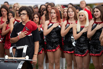 A band member along with the UNLV rebel girls listen to the national anthem.