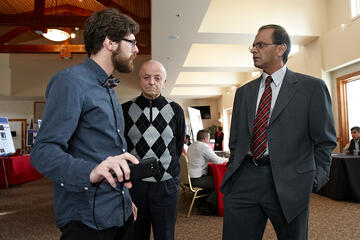 Smart Phone Augmented Reality Puzzle Performer: Student Raymond Imber shows his creation to Rama Venkat, interim dean of Engineering, and professor Evangelos Yfantis. Imber used “augmented reality” software to develop a game for smart phones. This technology allows computer-generated images to be superimposed onto a real-world environment or image. In Imber’s game, players must guide virtual creatures through a real-world environment. Second place in the computer science category.