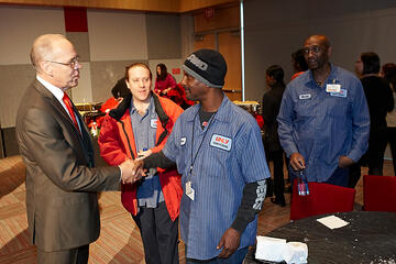 Neal Smatresk shaking hands with employees at holiday reception.