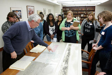 A library staff member presenting a special collections exhibit to students.