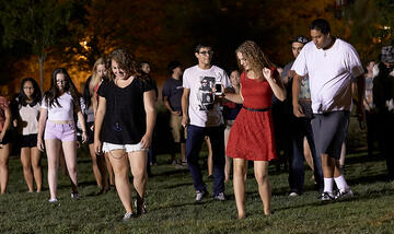Group of students walking during the night on the the grass lawn.