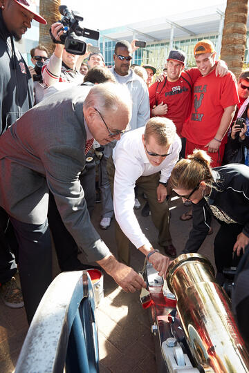 A group of people all painting the base of a canon.