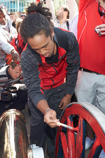 Student athlete painting the wheels of a canon red.