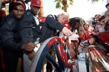 Group of student athletes painting the wheels of a canon.
