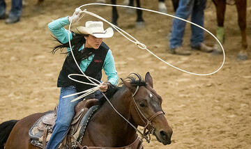 A female rodeo competitor preparing to throw a lasso.