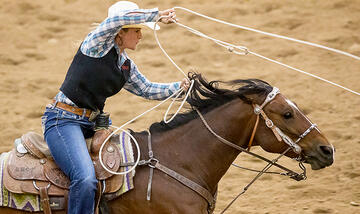 Female rodeo competitor about to throw her lasso during a competition.