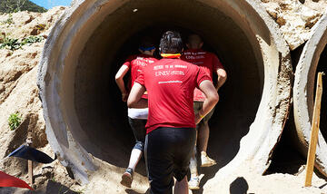 Tough Mudder competitors run into a tunnel.