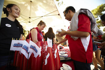 Students handing out megaphones and t-shirts during rally event.