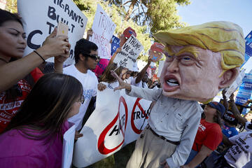 An anti-Trump protestor had a head that was as elaborate as it was difficult to see out of — he frequently had to be led through the terrain.