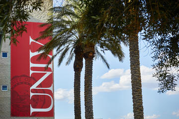 Palm trees lined up in front of a red "UNLV" sign