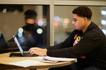 A student works on a computer in front of a window.