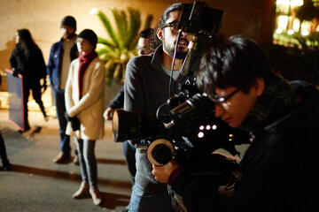 Two students look at a screen on a video camera during a shoot.