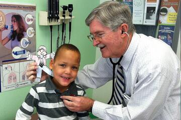 A doctor holds a stethoscope to a child
