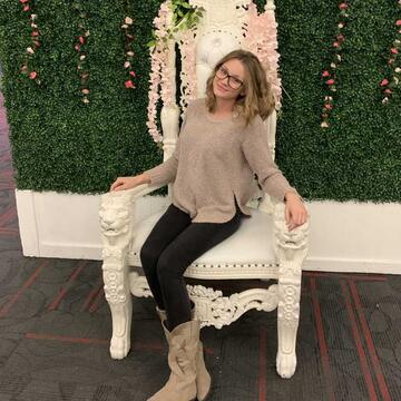 Student sitting on a chair in front of a green wall with pink flowers (Gabbie DeLong)