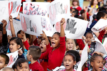 Crowd of young multi-racial kids holding up UNLV signs.