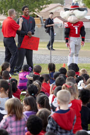 UNLV athlete giving a talk to a group of sitting children.