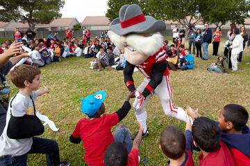 Hey Reb mascot running around giving high fives to young kids.