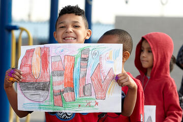 Front side view of a child holding up his UNLV artwork poster.
