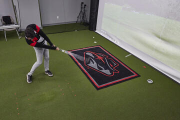 A golfer swings in front of a simulator screen.