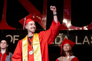 Student lifting arm in pride during commencement ceremony.