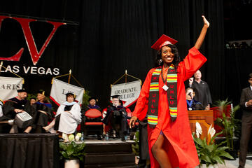 Student waving to audience during commencement ceremony.