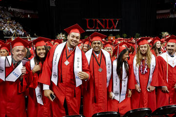 UNLV graduates pose and smile to audience.