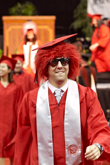 Male student with red wig during commencement.