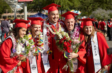 Students pose for camera with flowers during commencement.