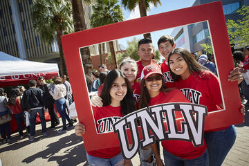 Students pose with a cardboard photo frame outside the Student Union.