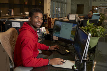 A student worker at a desk in the library.