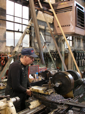 Man focused and working with traditional, industrial sized tools inside of a warehouse.