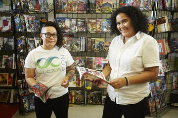 A student and a professor stand in front of a rack of comic books