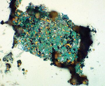 Microscoptic view of green-ish gold particles in a composite material
