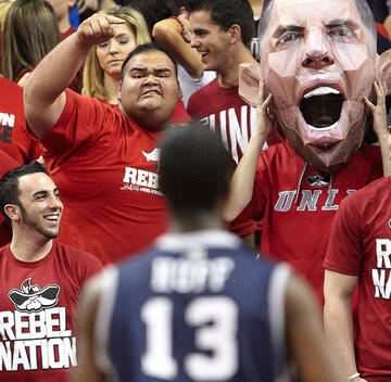 Group of students trying to make an opposing team basketball player lose his concentration in mid shot.