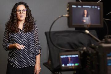A woman speaks into a videocamera