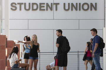 One girl pointing to a direction while others follow her line of sight. Outside of the Student Union.