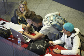 Group of students all focusing on the screen of a laptop.