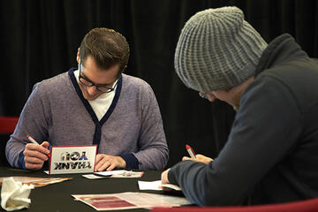 Two male students writing thank you cards.