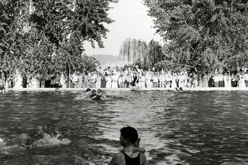 A crowd on the shore watches a family swim in the 1920s.