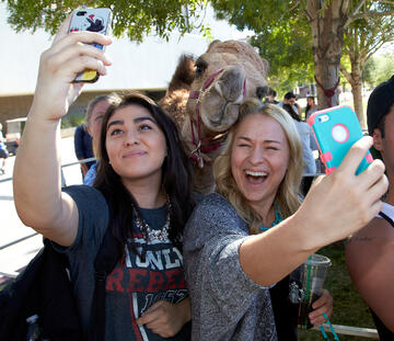 two girls take selfie with a camel