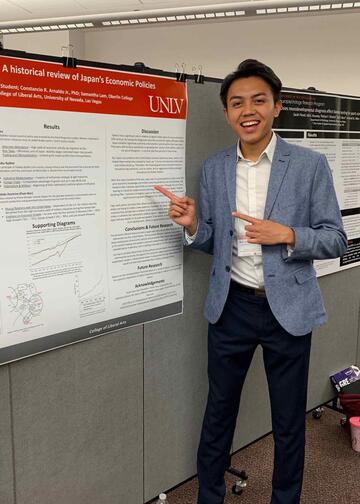 Kyle stands in front of a poster presentation at a research symposium